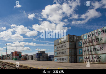 Cargo and shipping containers stacked high before being loaded onto freight trains for onward movement for export abroad. Stock Photo