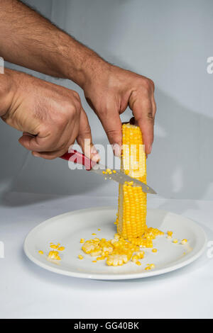 hands of man reeled one choclo with knife on a plate Stock Photo