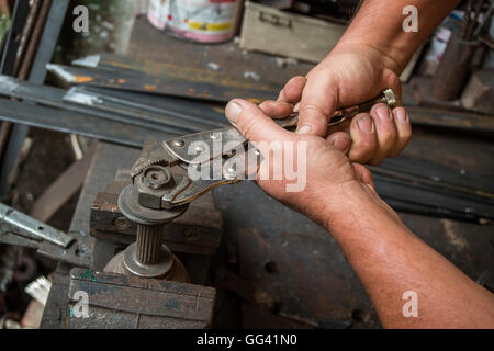 dirty hands of a worker who makes strength on a nut with a clamp in old workshop Stock Photo