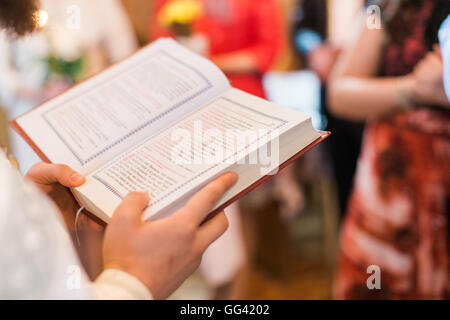 Orthodox priest during christening baptism reading book Stock Photo