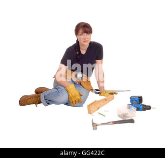 A middle age woman sitting on the floor and working with some tools, isolated for white background. Stock Photo