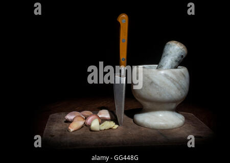 knife, mortar and garlic on a table with black background with space for your text Stock Photo