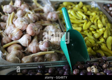 Olives and Garlic. Spicy olives, pickled garlic heads and green chilli pepper with sauce in a market stall. Close up of appetizers and pickles Stock Photo
