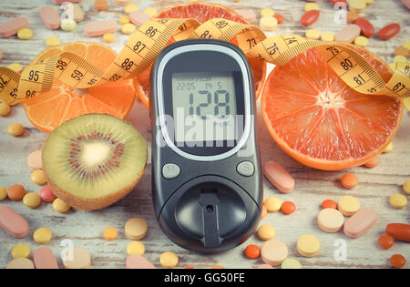 Vintage photo, Glucose meter with result of measurement sugar level, tape measure, fresh fruits and medical pills or supplements Stock Photo