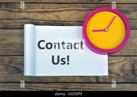 Clock and word Contact Us on wooden table Stock Photo