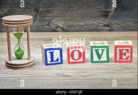 Hourglass and word love on wooden table Stock Photo