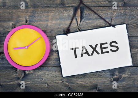 Taxes sign and clock on wooden table Stock Photo