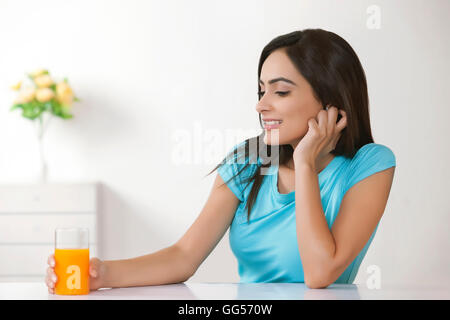 Happy young woman with glass of orange juice at home Stock Photo