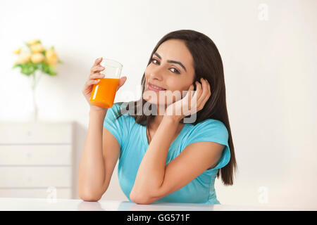 Portrait of beautiful young woman drinking orange juice at home Stock Photo