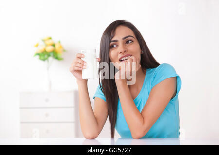 Young woman holding glass of milk at home Stock Photo