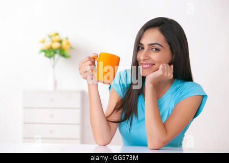 Portrait of happy young woman having coffee at home Stock Photo
