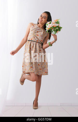 Portrait of happy young Indian woman holding flowers at home Stock Photo