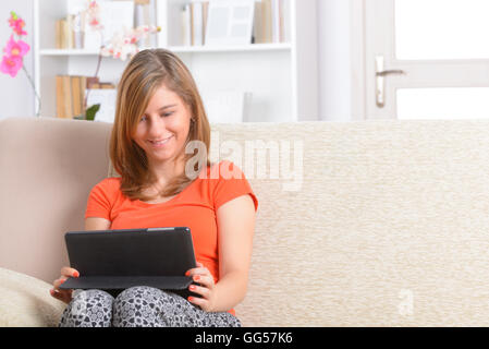 Young woman using tablet, sitting on sofa at home Stock Photo