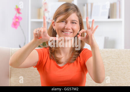 Beautiful smiling deaf woman using sign language showing L and O letters as a part of love word Stock Photo