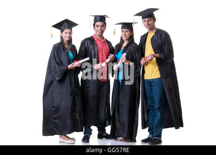 Full length portrait of graduate students holding diplomas against white background Stock Photo