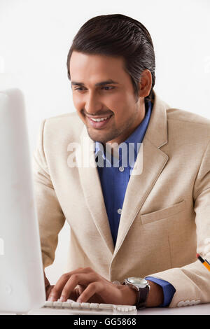 Smiling Indian businessman working on desktop PC in office Stock Photo
