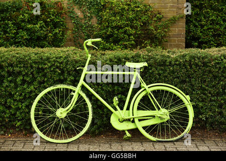 An old green painted bicycle parked against a hedge in The Netherlands Stock Photo