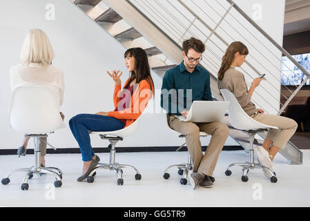 Business executives sitting on chairs busy in different activities Stock Photo