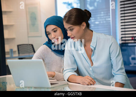 Two businesswomen looking at a laptop in an office Stock Photo