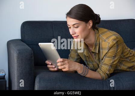 Young beautiful woman using a digital tablet on couch Stock Photo