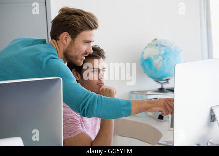 Two young businessmen working together on computer in an office Stock Photo