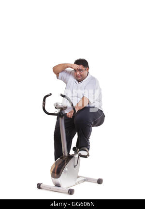 Obese man on exercise bike Stock Photo