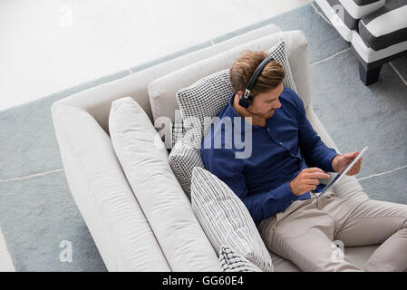 Young man sitting on couch using a digital tablet Stock Photo