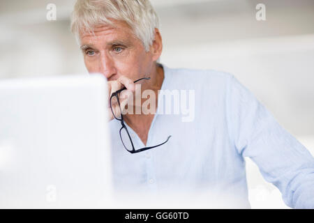Serious senior man looking at laptop on table Stock Photo