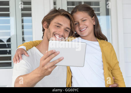 Happy father with his little daughter taking a selfie with digital tablet at home
