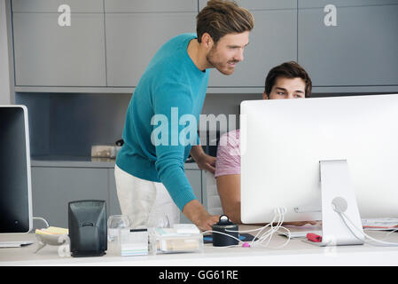 Two young businessmen working together on computer in an office Stock Photo