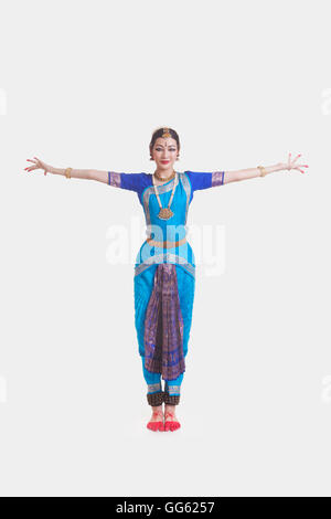 Portrait of young woman with arms outstretched performing Bharatanatyam against white background Stock Photo