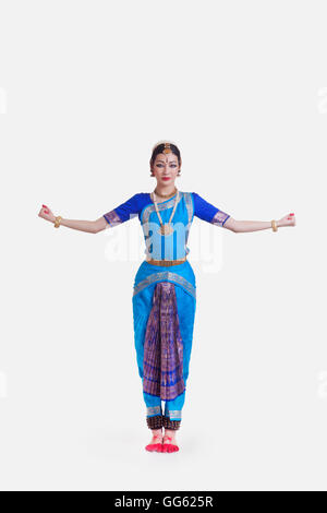 Portrait of young woman with arms outstretched performing Bharatanatyam against white background Stock Photo