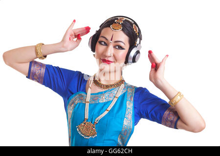 Bharatanatyam dancer wearing headphone while performing over white background Stock Photo