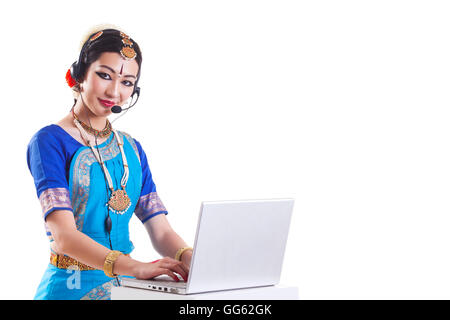 Portrait of Bharatanatyam dancer wearing headset while using laptop over white background Stock Photo