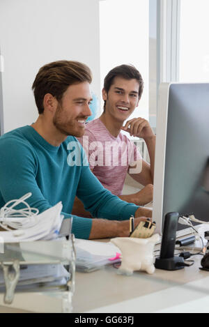 Happy young businessmen working together on computer in an office Stock Photo