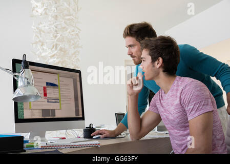 Two young businessmen working together on computer in an office Stock Photo