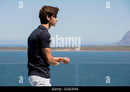 Young man standing on balcony outdoors Stock Photo