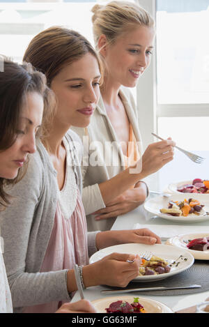 Three beautiful women having lunch at dining table Stock Photo