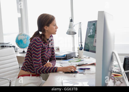 Side profile of a businesswoman working on a desktop pc in office Stock Photo