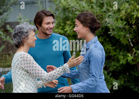 Happy mature woman meet with young couple outside Stock Photo