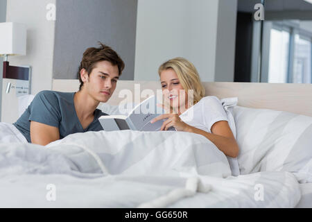 Young couple reading a book on the bed Stock Photo