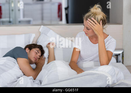 Young woman looking at her husband sleeping on the bed Stock Photo