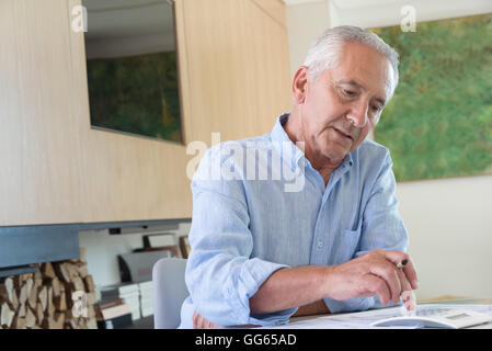 Senior man using a calculator while doing paperwork at home Stock Photo