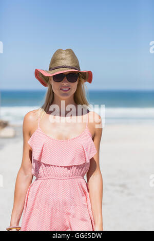 Beautiful young woman standing on sunny beach Stock Photo
