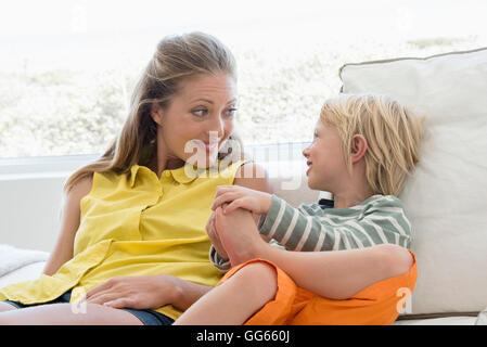 Happy mother and son sitting on couch in living room Stock Photo