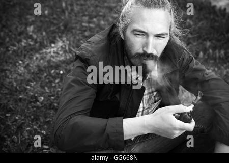 Asian man smoking a pipe, black and white photo with selective focus Stock Photo