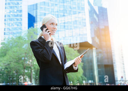 Businesswoman using a mobile phone in financial district Stock Photo