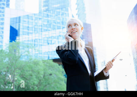 Businesswoman using a mobile phone in financial district Stock Photo