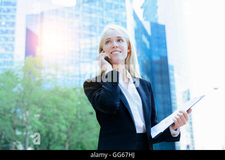 Businesswoman using a mobile phone in financial district Stock Photo