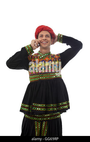 Male dandiya dancer talking on a mobile phone Stock Photo - Alamy